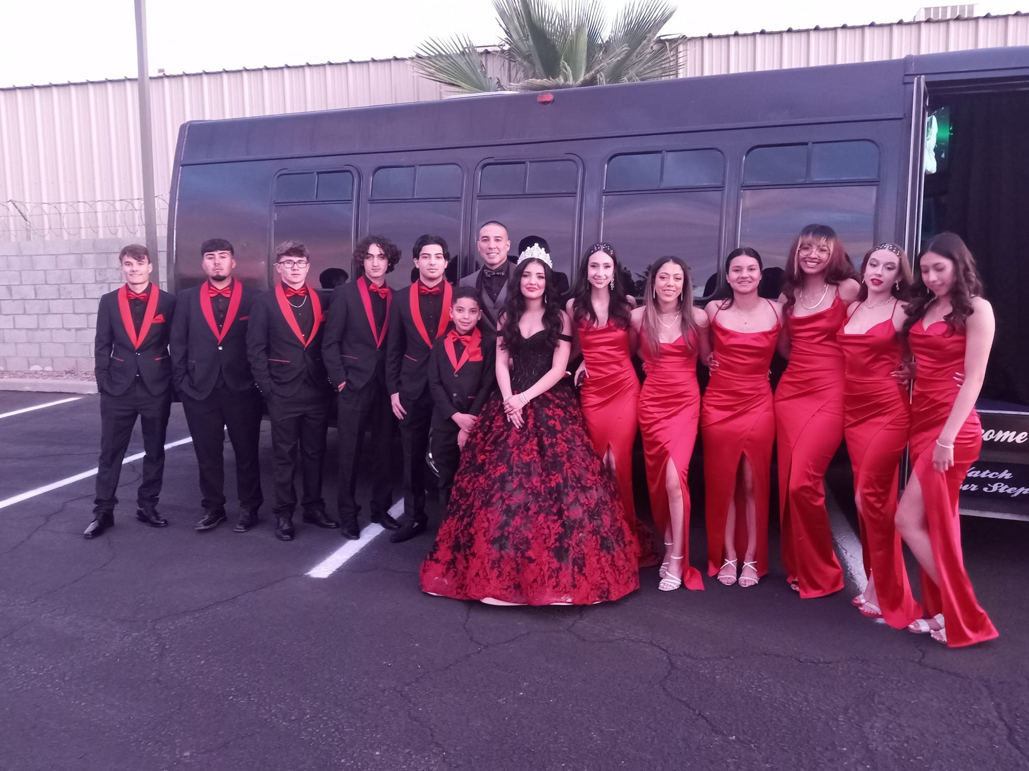 Quincea&ntilde;era group in red dresses outside party bus